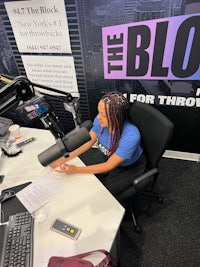 a woman sits at a desk in front of a microphone