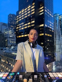 a woman with a dj deck in front of a city skyline