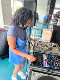 a woman in a blue dress playing a dj set