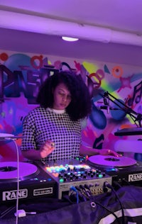 a woman djing in front of a colorful wall